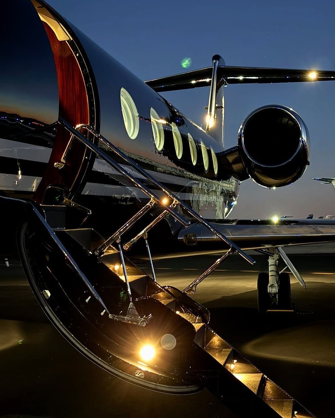 Private jet with airstair lit at dusk on the ramp